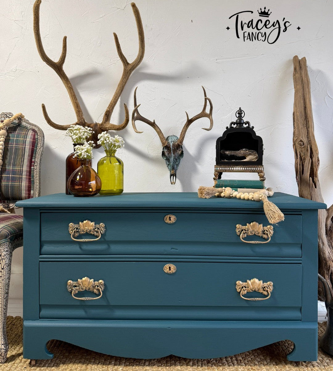 Blue dresser with gold handles in a room with decorative elements like antlers and vases.
