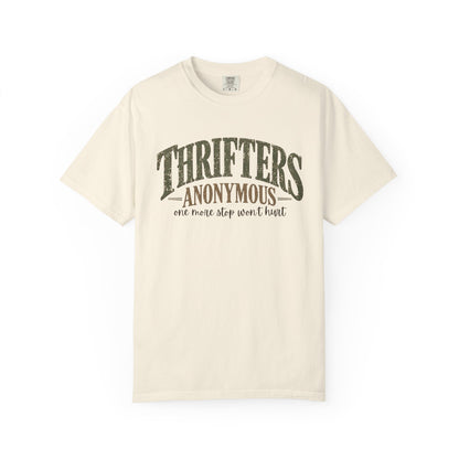 An off-white short-sleeve t-shirt with a distressed dark green graphic on the front that reads 'THRIFTERS ANONYMOUS' and 'one more stop won't hurt'.