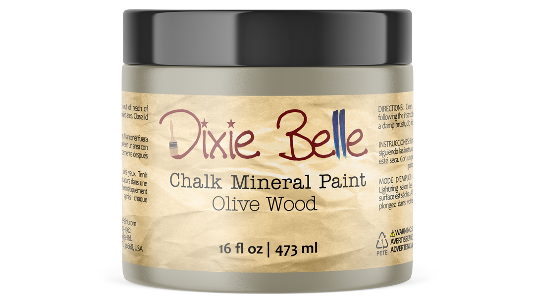 A jar of Dixie Belle Chalk Mineral Paint in the Olive Wood color, featuring a textured tan paper label and a black lid, shown on a clean white background.