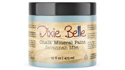 A jar of Dixie Belle Chalk Mineral Paint in the 'Savannah Mist' color, featuring a light blue paint jar, a black lid, and a beige label with red and black text.