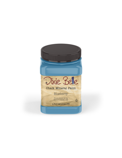 A jar of Dixie Belle Chalk Mineral Paint in the Blueberry color, featuring a black lid and a beige label, set against a plain white background.