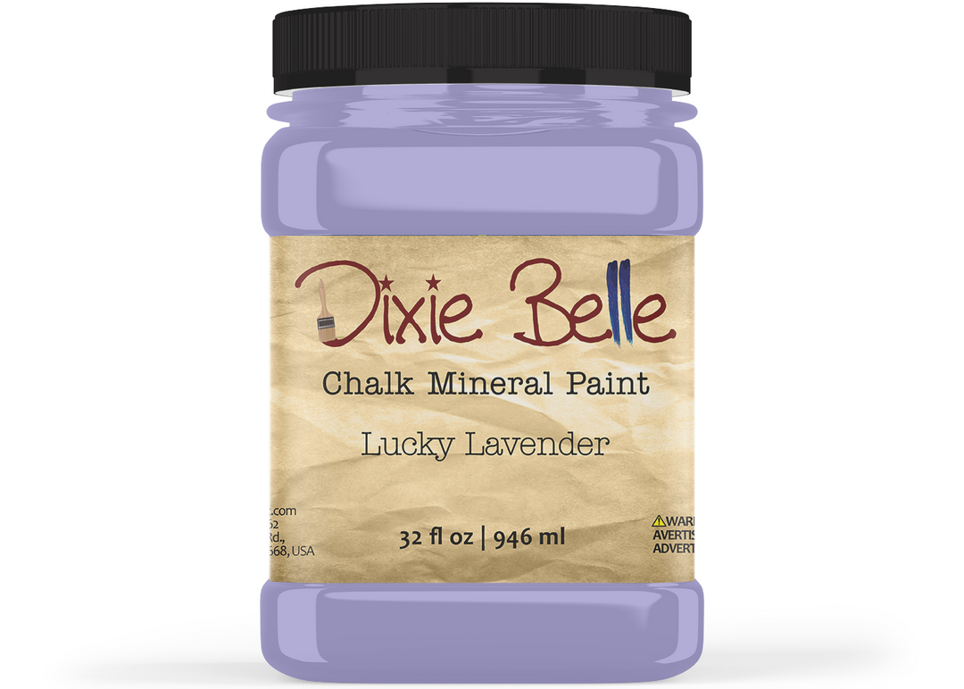 A jar of Dixie Belle Chalk Mineral Paint in the shade Lucky Lavender, featuring a black lid and a beige label, shown on a white background.