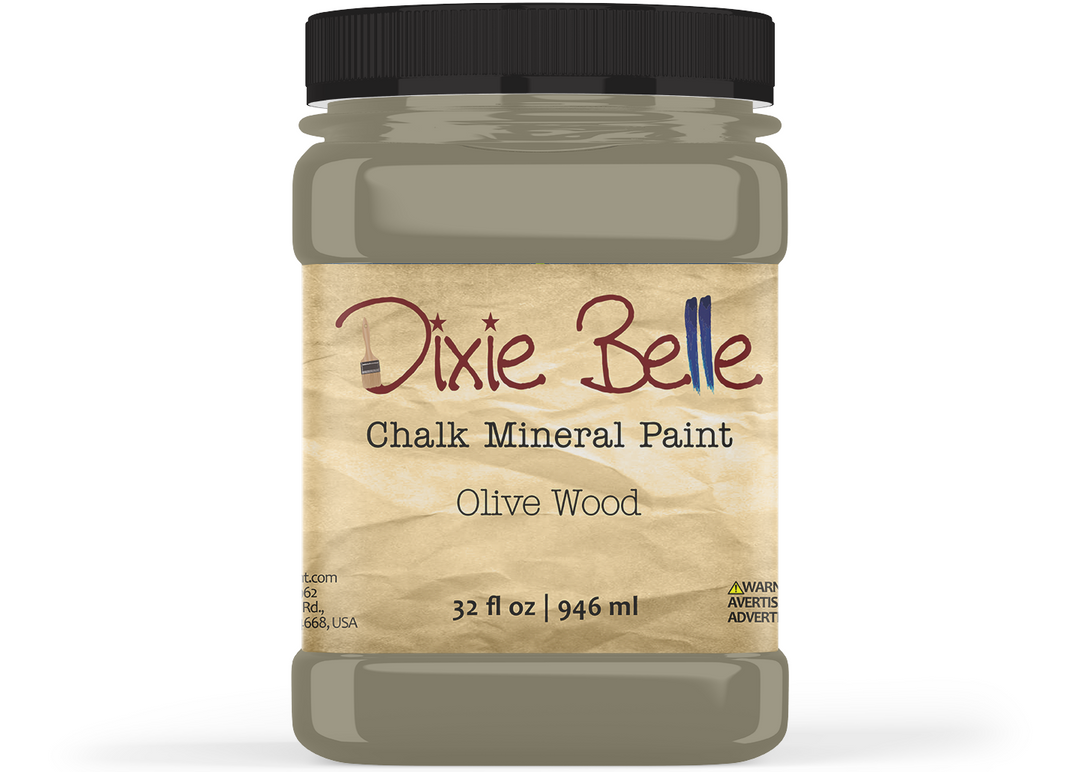 A jar of Dixie Belle Chalk Mineral Paint in the color 'Olive Wood', featuring a black lid and a textured beige label, shown on a plain white background.