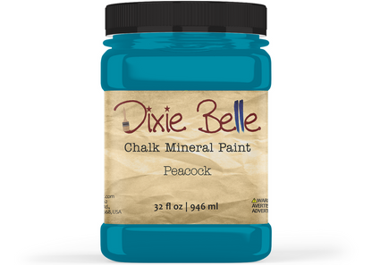A jar of Dixie Belle Chalk Mineral Paint in the color Peacock, featuring a black lid and a beige textured label, shown on a white background.