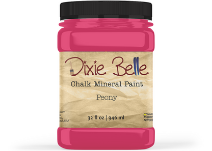 A jar of Dixie Belle Chalk Mineral Paint in the shade Peony, featuring a bright pink paint jar with a black lid and a beige textured label.