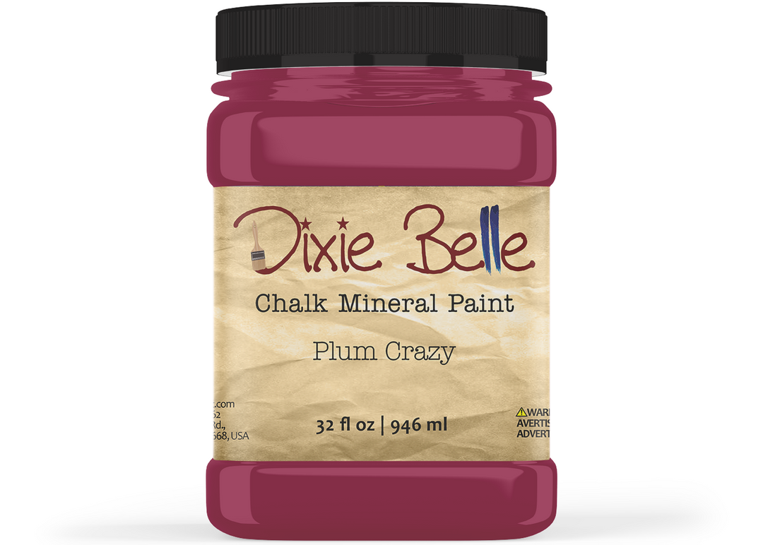 A jar of Dixie Belle Chalk Mineral Paint in the shade Plum Crazy, featuring a black lid and a beige textured label, shown on a white background.