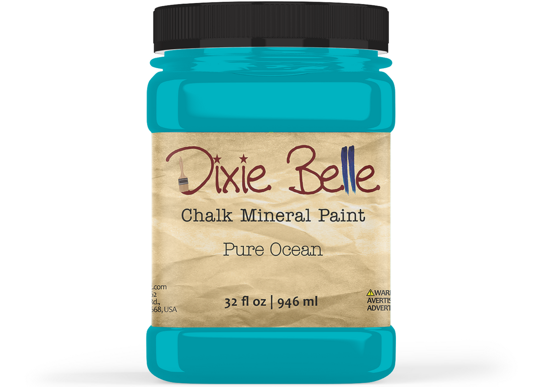 A jar of Dixie Belle Chalk Mineral Paint in the color 'Pure Ocean', featuring a bright turquoise blue paint visible through the clear jar, a black lid, and a beige label with brown and black text.