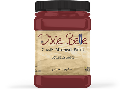 A jar of Dixie Belle Chalk Mineral Paint in the color Rustic Red, featuring a black lid and a beige textured label, shown on a white background.