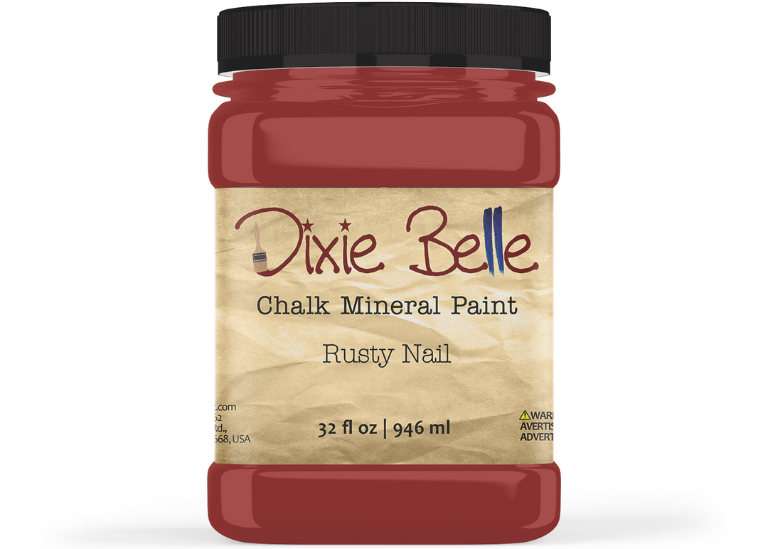 A jar of Dixie Belle Chalk Mineral Paint in the color 'Rusty Nail', featuring a black lid and a beige textured label, shown on a white background.