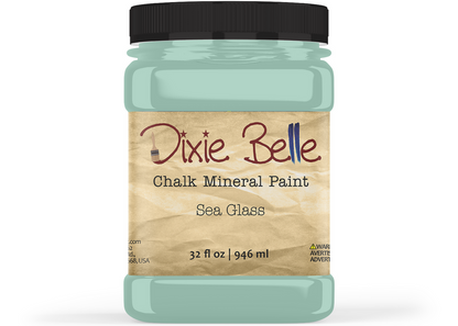 A jar of Dixie Belle Chalk Mineral Paint in the 'Sea Glass' color, featuring a black lid and a beige label with brown and blue text, set against a plain white background.