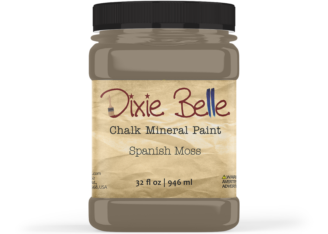 A jar of Dixie Belle Chalk Mineral Paint in the color 'Spanish Moss', featuring a black lid and a beige label with brown and blue text, set against a plain white background.