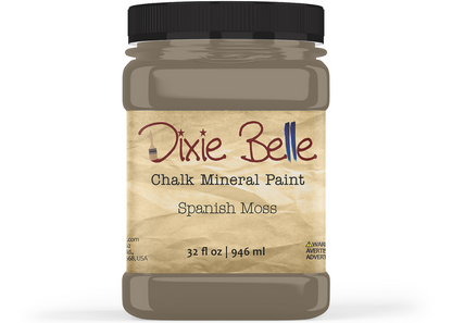 A jar of Dixie Belle Chalk Mineral Paint in the color 'Spanish Moss', featuring a black lid and a beige label with brown and blue text, set against a plain white background.