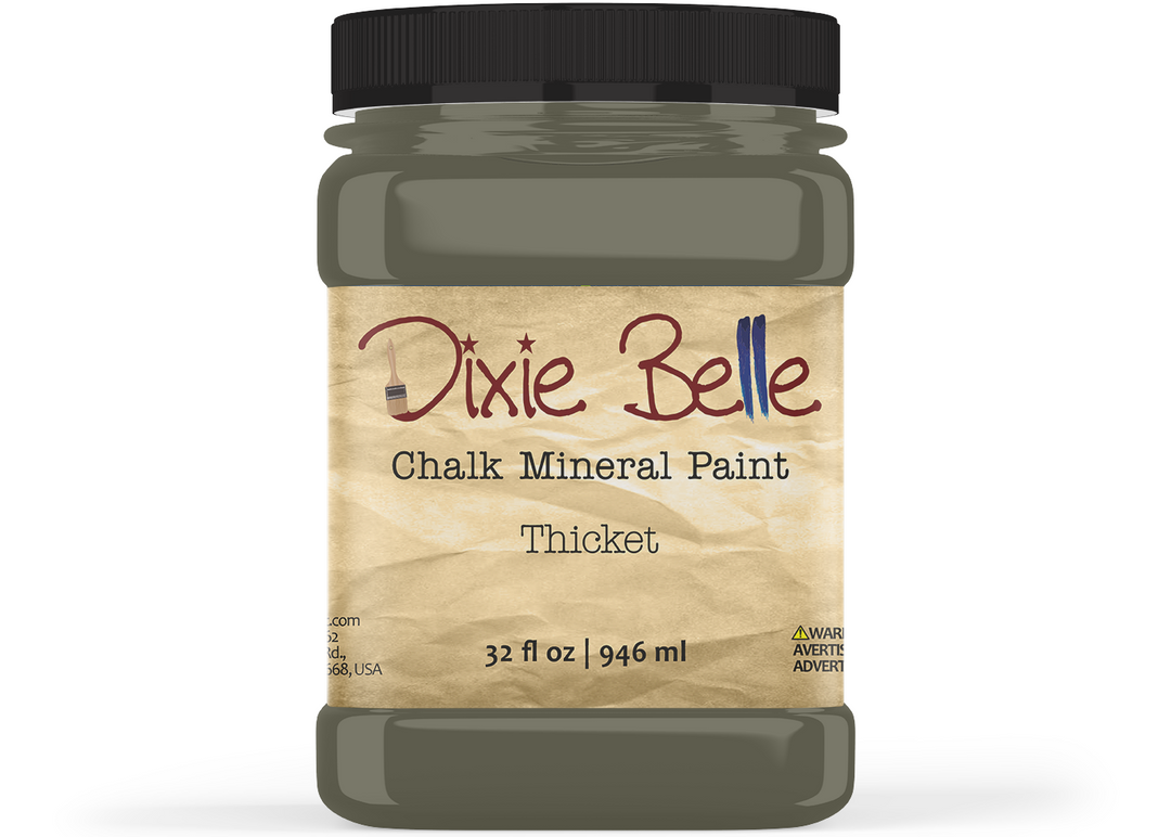 A jar of Dixie Belle Chalk Mineral Paint in the color Thicket, featuring a black lid and a beige textured label on a white background.