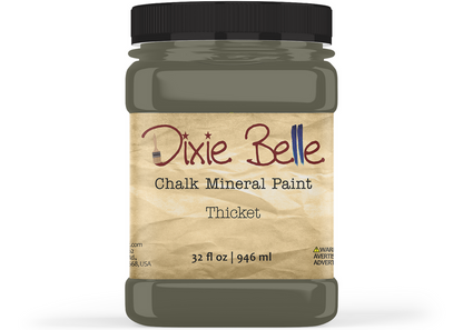 A jar of Dixie Belle Chalk Mineral Paint in the color Thicket, featuring a black lid and a beige textured label on a white background.