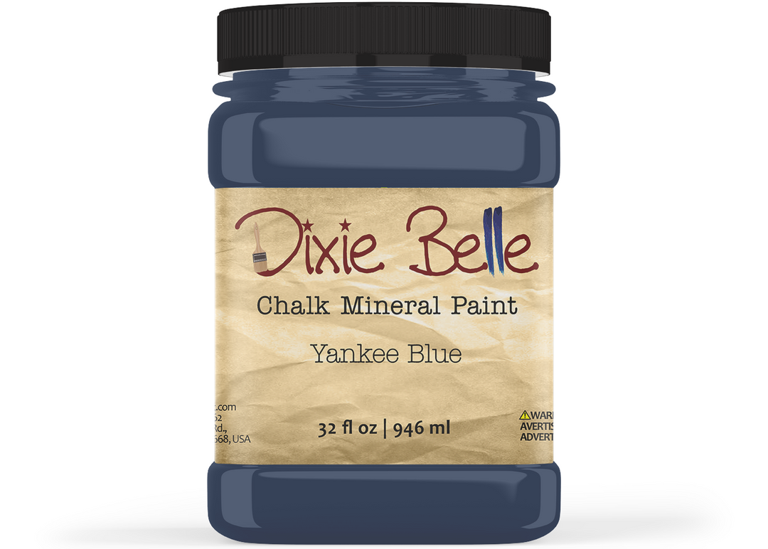 A jar of Dixie Belle Chalk Mineral Paint in the color Yankee Blue, featuring a black lid and a beige textured label, shown on a white background.