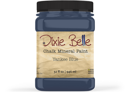 A jar of Dixie Belle Chalk Mineral Paint in the color Yankee Blue, featuring a black lid and a beige textured label, shown on a white background.