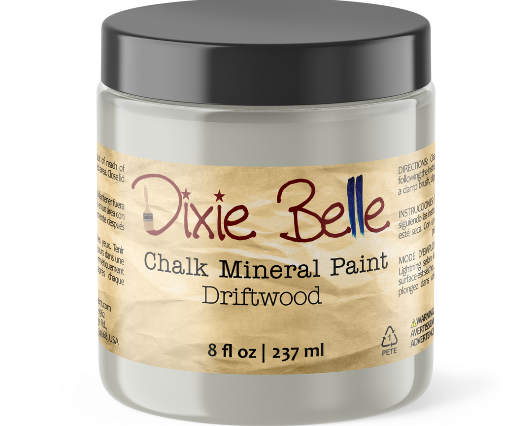A jar of Dixie Belle Chalk Mineral Paint in the color Driftwood, featuring a black lid and a beige label with the brand name in red script.