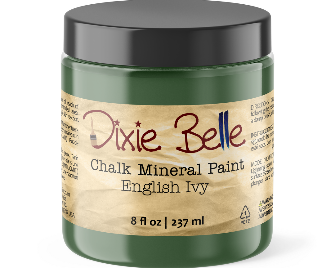 A jar of Dixie Belle Chalk Mineral Paint in the color English Ivy, featuring a dark green jar, a black lid, and a beige label with red and blue lettering.