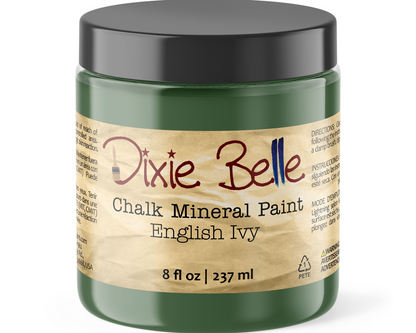 A jar of Dixie Belle Chalk Mineral Paint in the color English Ivy, featuring a dark green jar, a black lid, and a beige label with red and blue lettering.