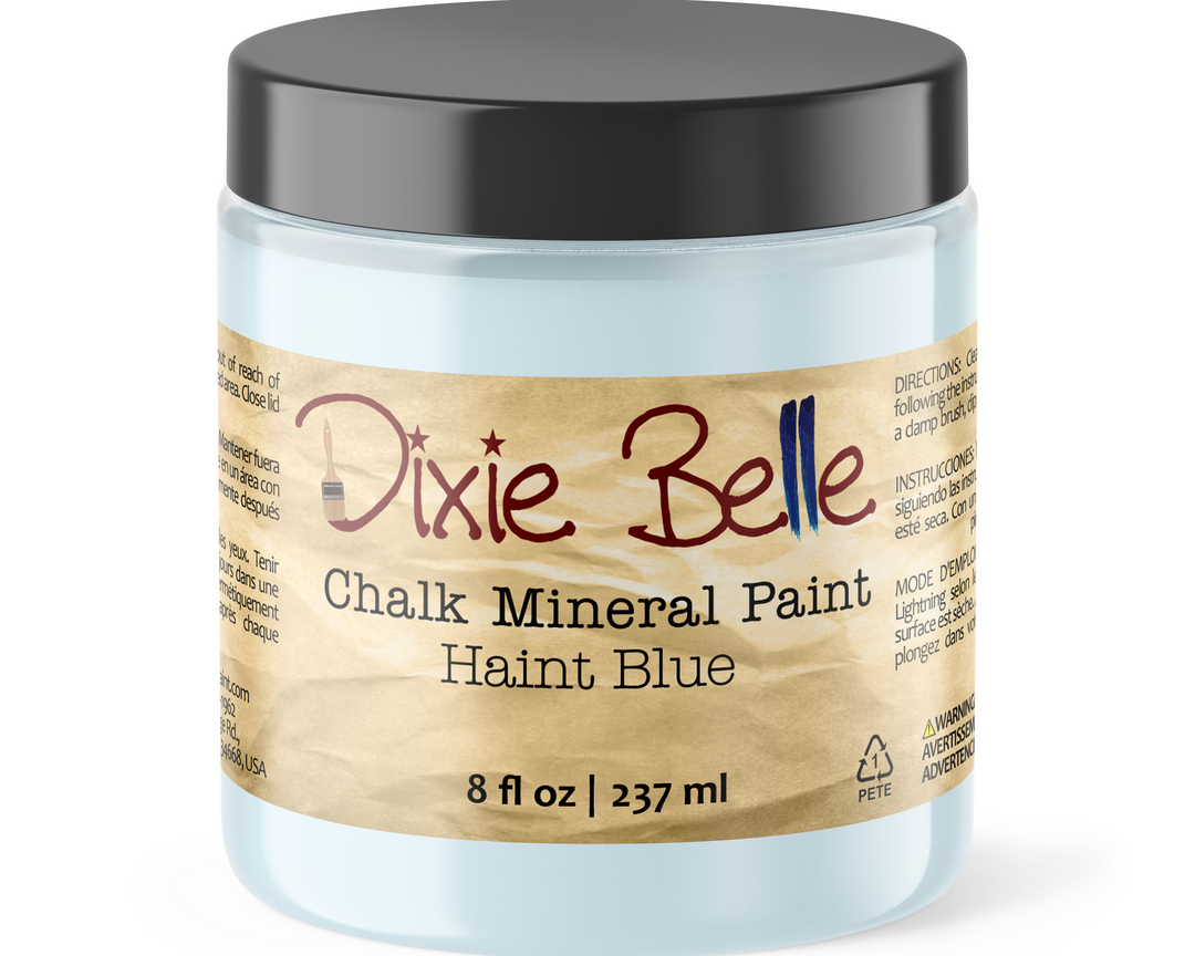 A jar of Dixie Belle Chalk Mineral Paint in the color Haint Blue, featuring a light blue container, a black lid, and a brown paper-textured label.