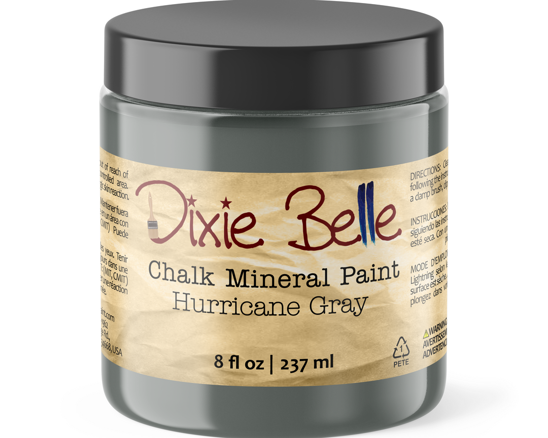 A jar of Dixie Belle Chalk Mineral Paint in the color Hurricane Gray, featuring a dark gray container and a beige label with red and blue lettering.