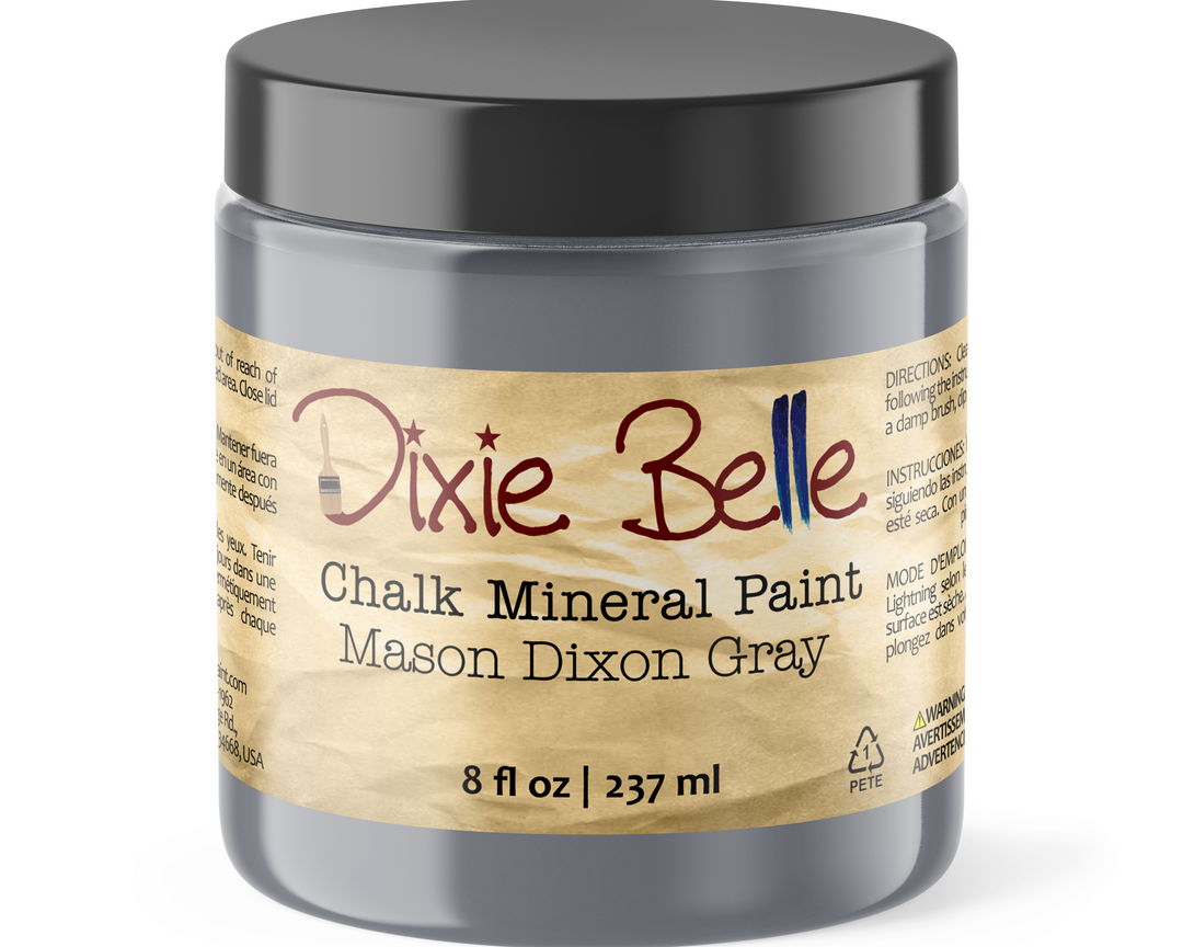 A jar of Dixie Belle Chalk Mineral Paint in the color Mason Dixon Gray, featuring a black lid and a beige label with red and blue lettering.