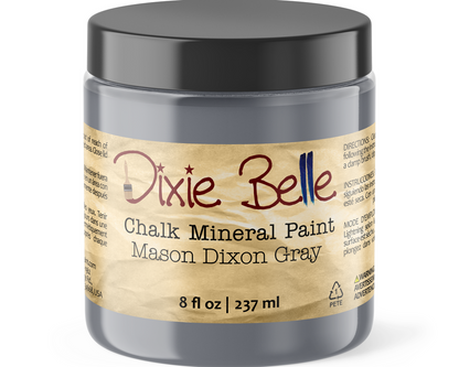 A jar of Dixie Belle Chalk Mineral Paint in the color Mason Dixon Gray, featuring a black lid and a beige label with red and blue lettering.