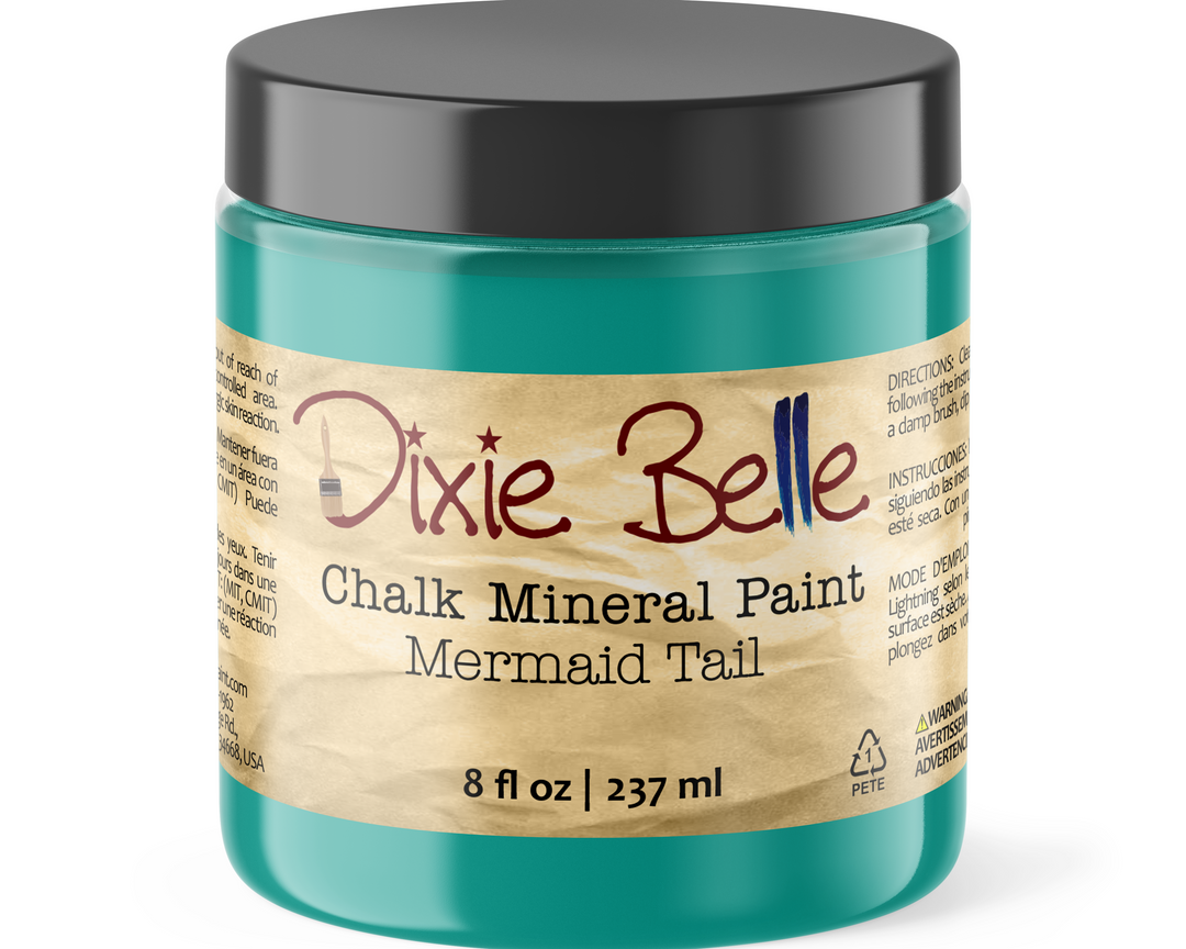 A jar of Dixie Belle Chalk Mineral Paint in the Mermaid Tail color, featuring a teal-green container, a black lid, and a beige paper label with red and black text.