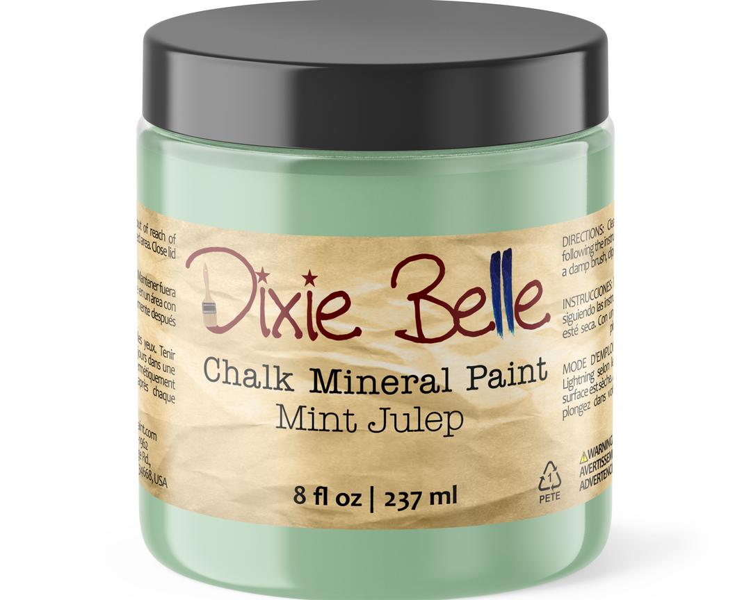 A jar of Dixie Belle Chalk Mineral Paint in the shade Mint Julep, featuring a light mint green container, a black lid, and a beige paper label with red and blue lettering.