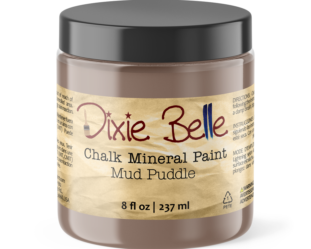 A jar of Dixie Belle Chalk Mineral Paint in the Mud Puddle shade, featuring a black lid and a beige label with brown and red text.