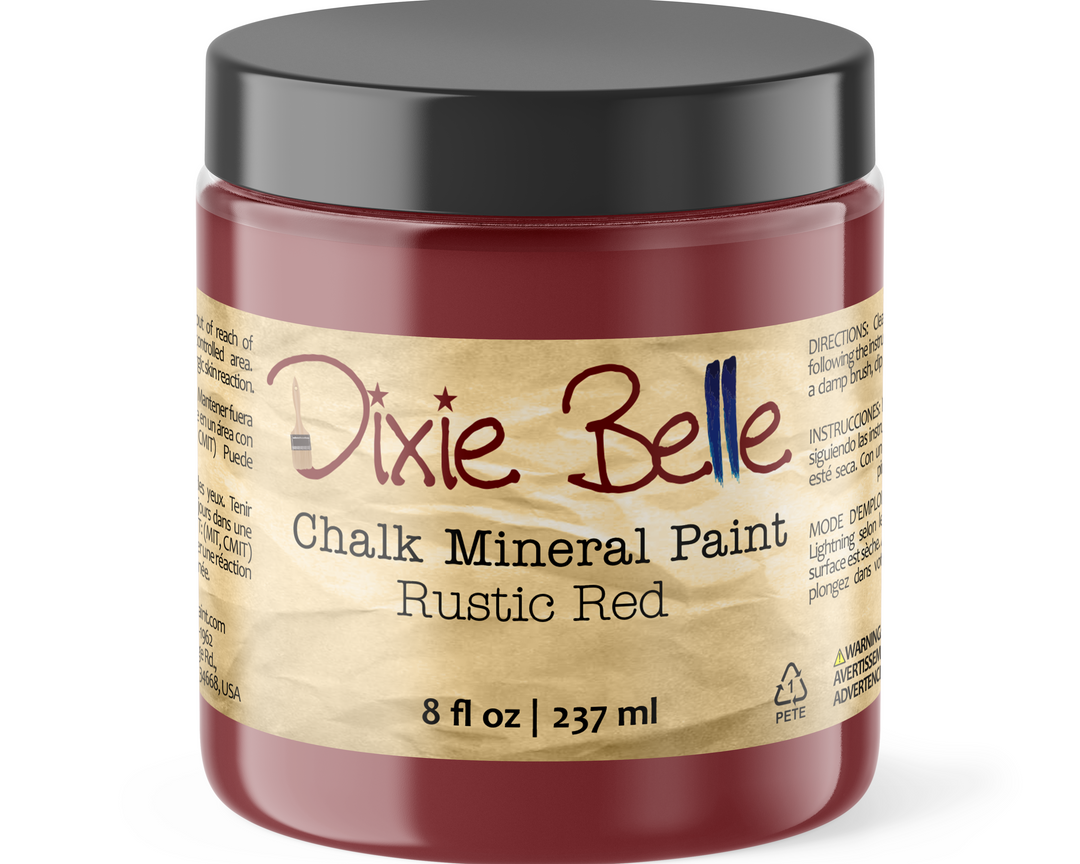 A jar of Dixie Belle Chalk Mineral Paint in the color Rustic Red, featuring a black lid and a beige label with red and black text.