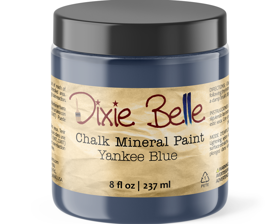 A jar of Dixie Belle Chalk Mineral Paint in the color Yankee Blue, featuring a black lid and a beige label with red and black text.