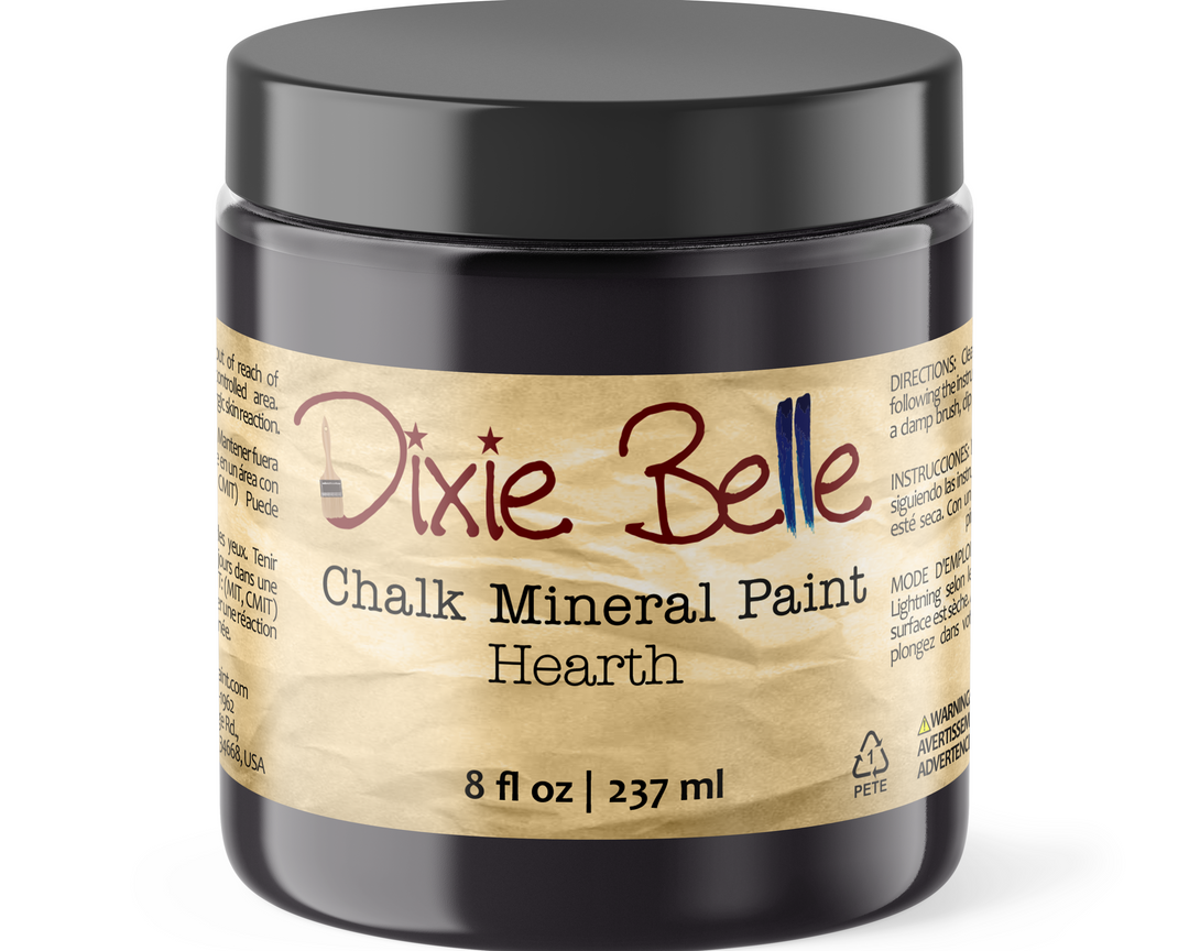 A black plastic jar of Dixie Belle Chalk Mineral Paint in the 'Hearth' color, featuring a textured tan paper label with red and blue script branding.