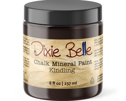 A jar of Dixie Belle Chalk Mineral Paint in the color 'Kindling' with an 8 fl oz capacity. The product is housed in a dark brown translucent plastic jar with a black screw-on lid and a textured tan paper-style label.