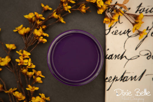 Purple container lid on a dark surface with yellow flowers and cursive text