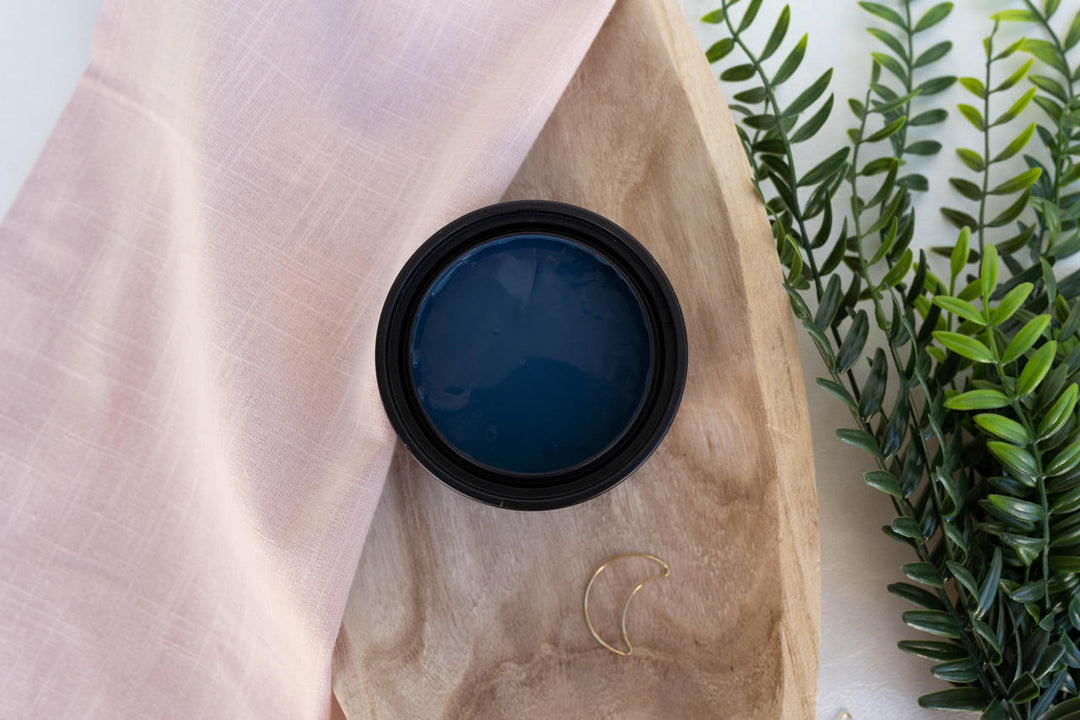 Blue Moon Terra Clay Paint, styled on a beige paper bag with a pink cloth and green leaves in the background.