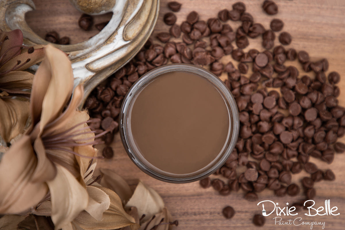 Brown paint sample with chocolate chips and flowers on a wooden surface, featuring the Dixie Belle Paint Company logo.