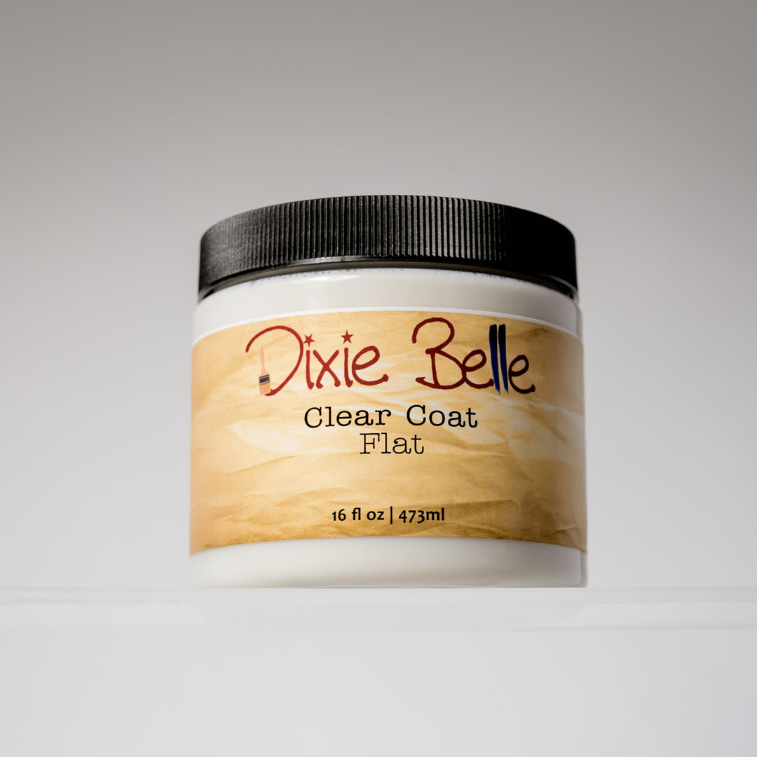 A white plastic jar of Dixie Belle Clear Coat Flat with a black ribbed lid and a light wood-grain label, set against a neutral gray background.