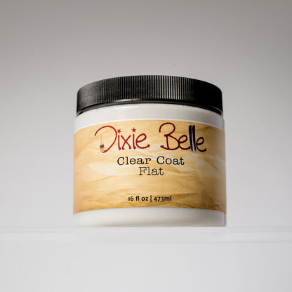 A white plastic jar of Dixie Belle Clear Coat Flat with a black ribbed lid and a light wood-grain label, set against a neutral gray background.