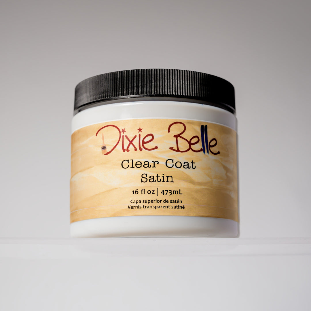 A white plastic jar of Dixie Belle Clear Coat Satin with a black ribbed lid and a beige label, photographed on a neutral light gray background.