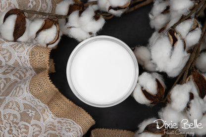 White jar of paint on a dark surface with cotton and burlap