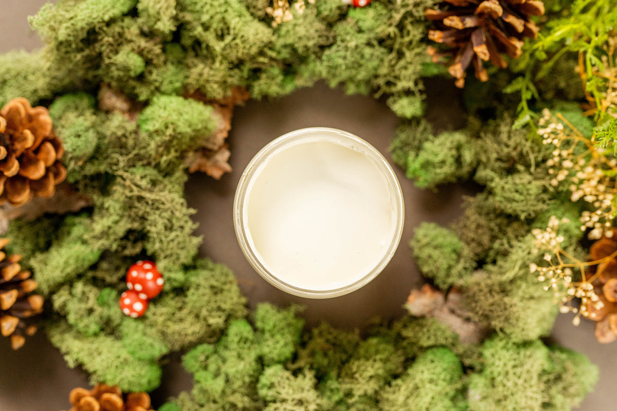 Moss wreath with pinecones and berries around a cream paint jar