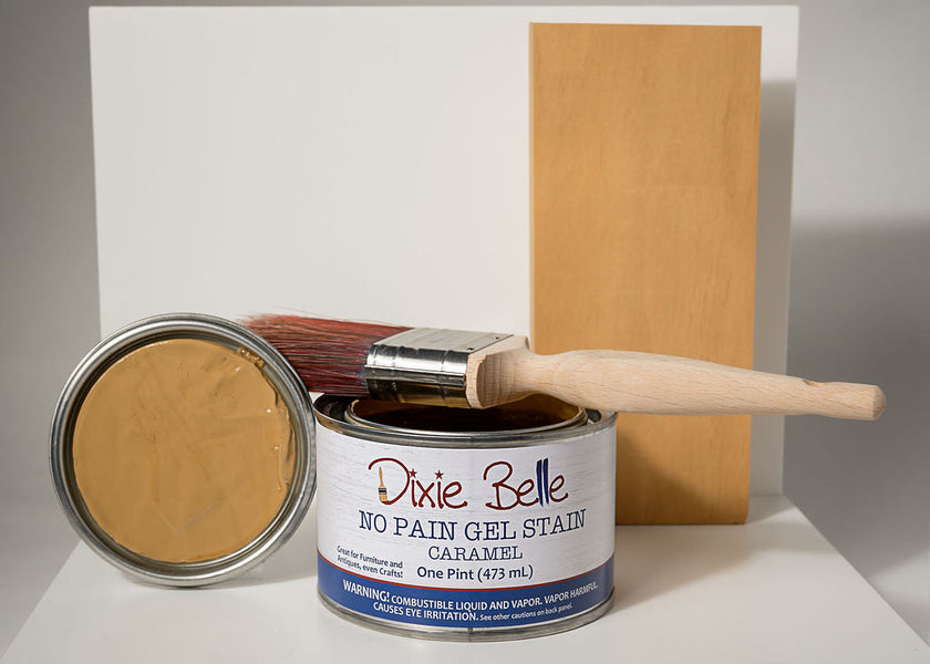 Can of Dixie Belle No Pain Gel Stain Caramel with a brush and wood sample on a white background
