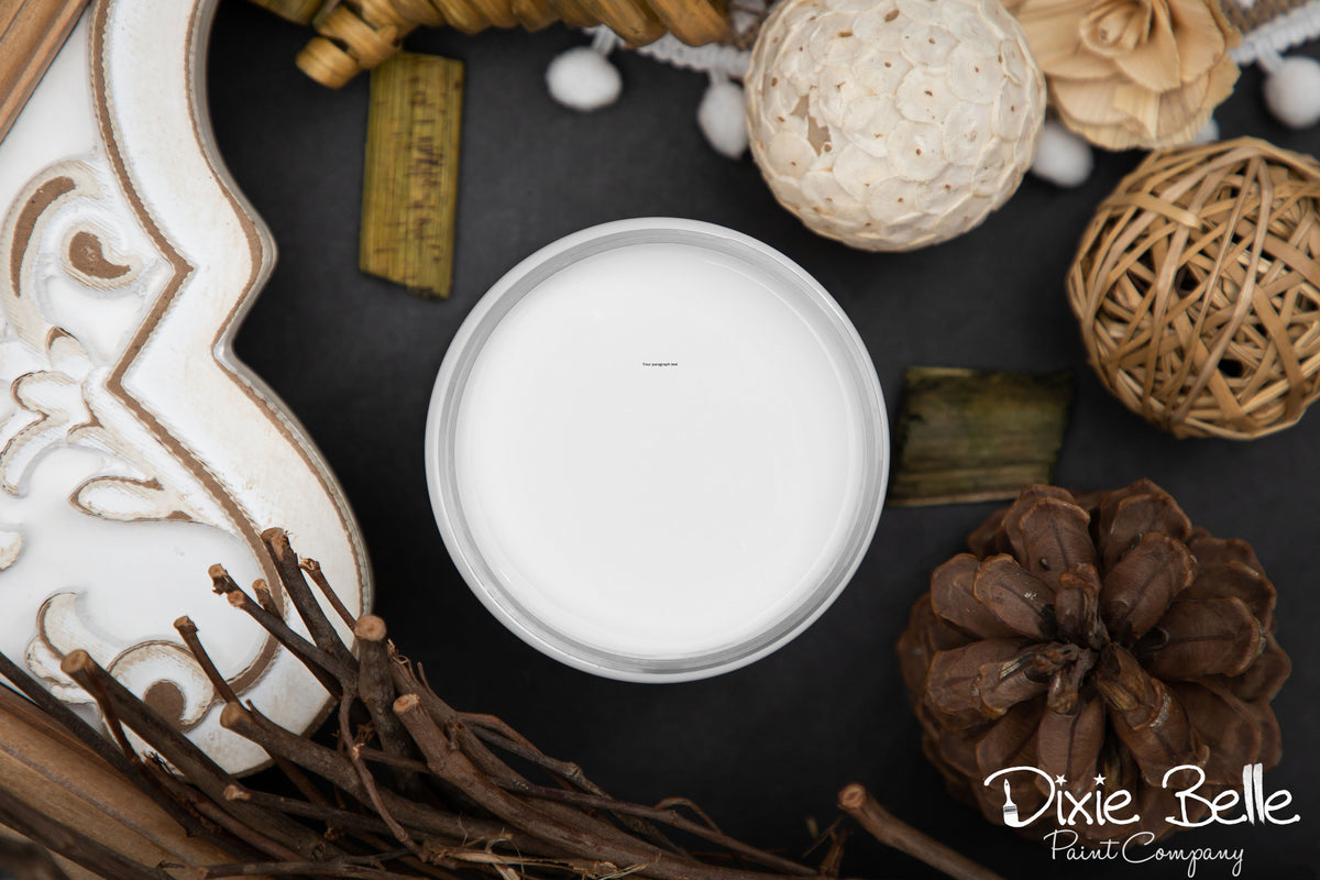 Fluff white color paint jar in a decorative container surrounded by natural elements on a dark surface with 'Dixie Belle Paint Company' branding.