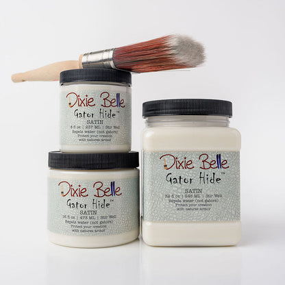 Three jars of Dixie Belle Gator Hide clear coat with a paintbrush resting across the top jar, set against a clean white background.