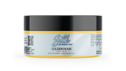 A jar of Silk All-In-One Mineral Paint in the Golden Hour shade, featuring a black lid, a white label with gold accents, and a yellow-gold base, shown on a clean white background.
