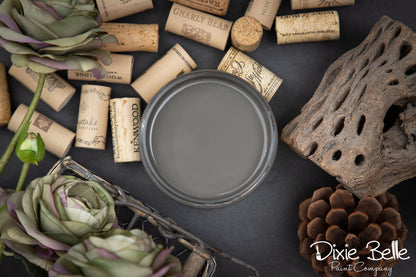 Dark gray paint can with wine corks, decorative elements, and 'Dixie Belle Paint Company' branding on a dark surface.