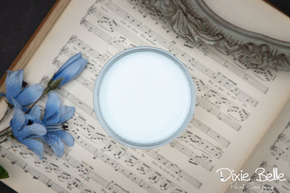 Jar of haint blue paint on sheet music with blue flowers, featuring 'Dixie Belle' branding.