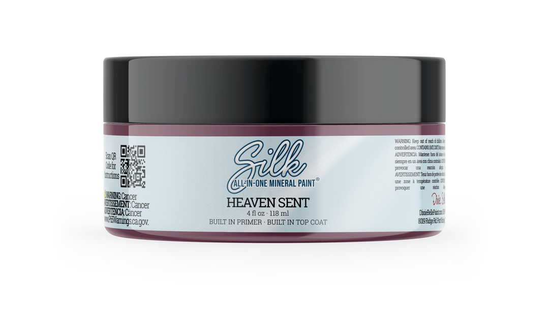 A jar of Silk All-In-One Mineral Paint in the shade Heaven Sent, featuring a black lid and a white label with purple accents, set against a plain white background.