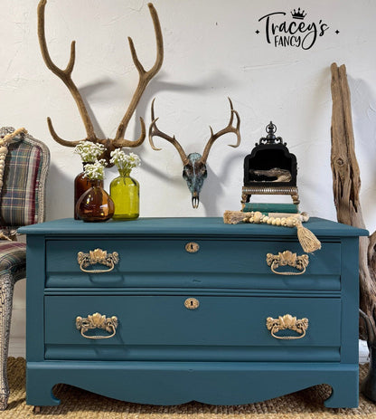 Blue dresser with gold handles in a room with decorative elements like antlers and vases.